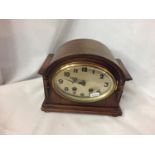 A VINTAGE WOODEN CASED CLOCK WITH A BRASS OVAL FACE, WITH PENDULUM, NO KEY. WORKING AT TIME OF