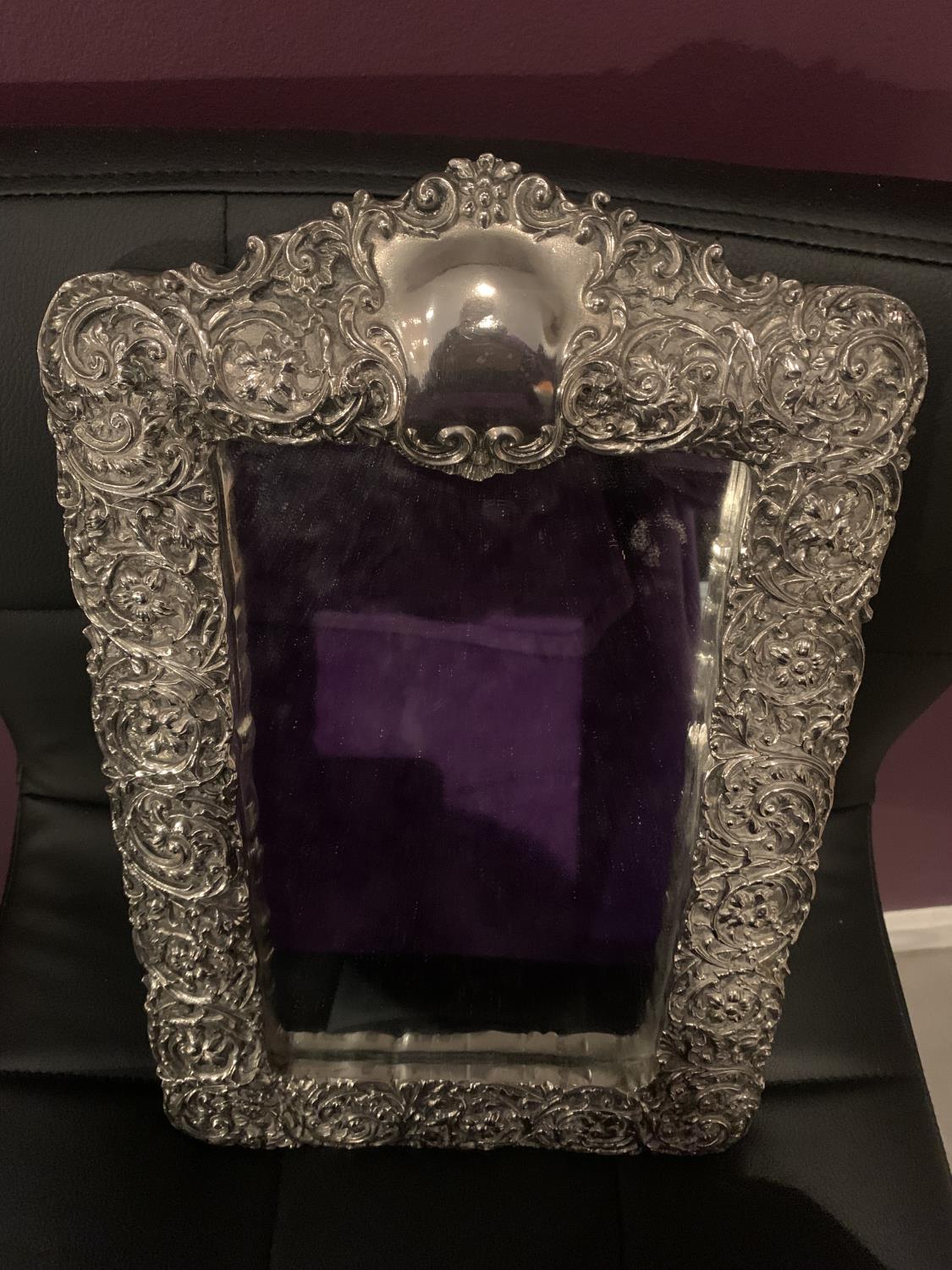 AN ORNATE SILVER FRAMED MIRROR WITH INDISTINCT HALLMARK 25CM X 39CM