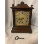 A DECORATIVE OAK CASED MANTLE CLOCK WITH GILT FACE AND ROMAN NUMERALS AND A KEY