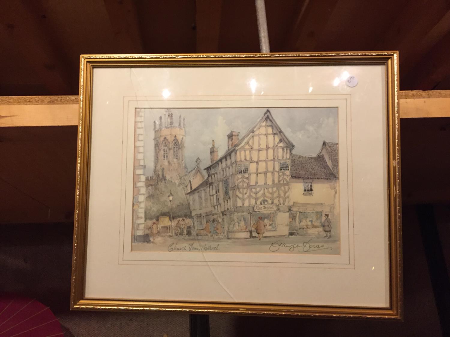 A FRAMED PRINT OF CHURCH LANE, NANTWICH, SIGNED TO THE BOTTOM RIGHT (GLASS A/F)