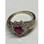 A 9 CARAT GOLD RING WITH A HEART SHAPED RUBY SURROUNDED BY DIAMONDS WITH DIAMONDS ON THE SHOULDERS