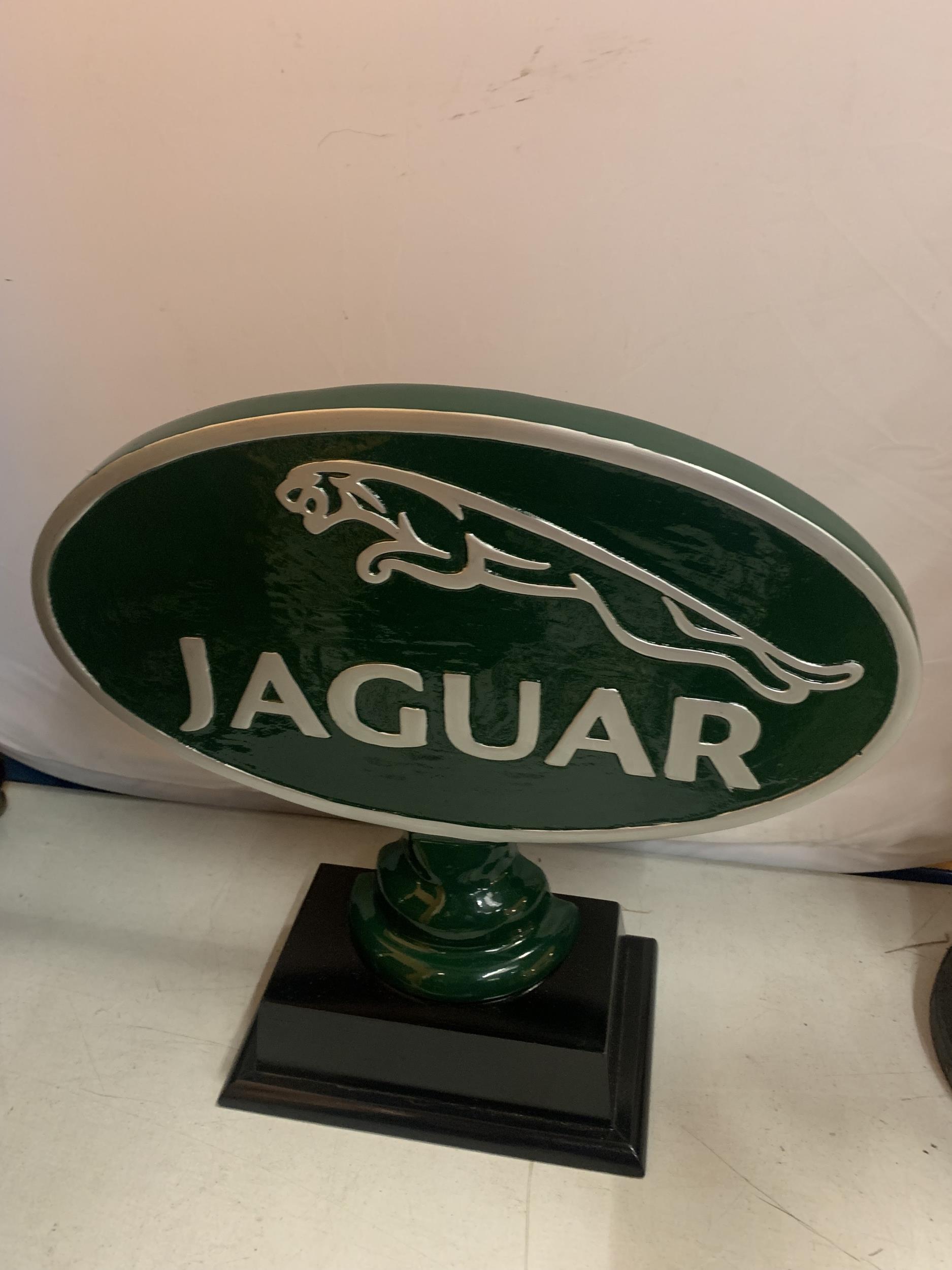 A LARGE CAST JAGUAR SIGN ON A WOODEN BASE