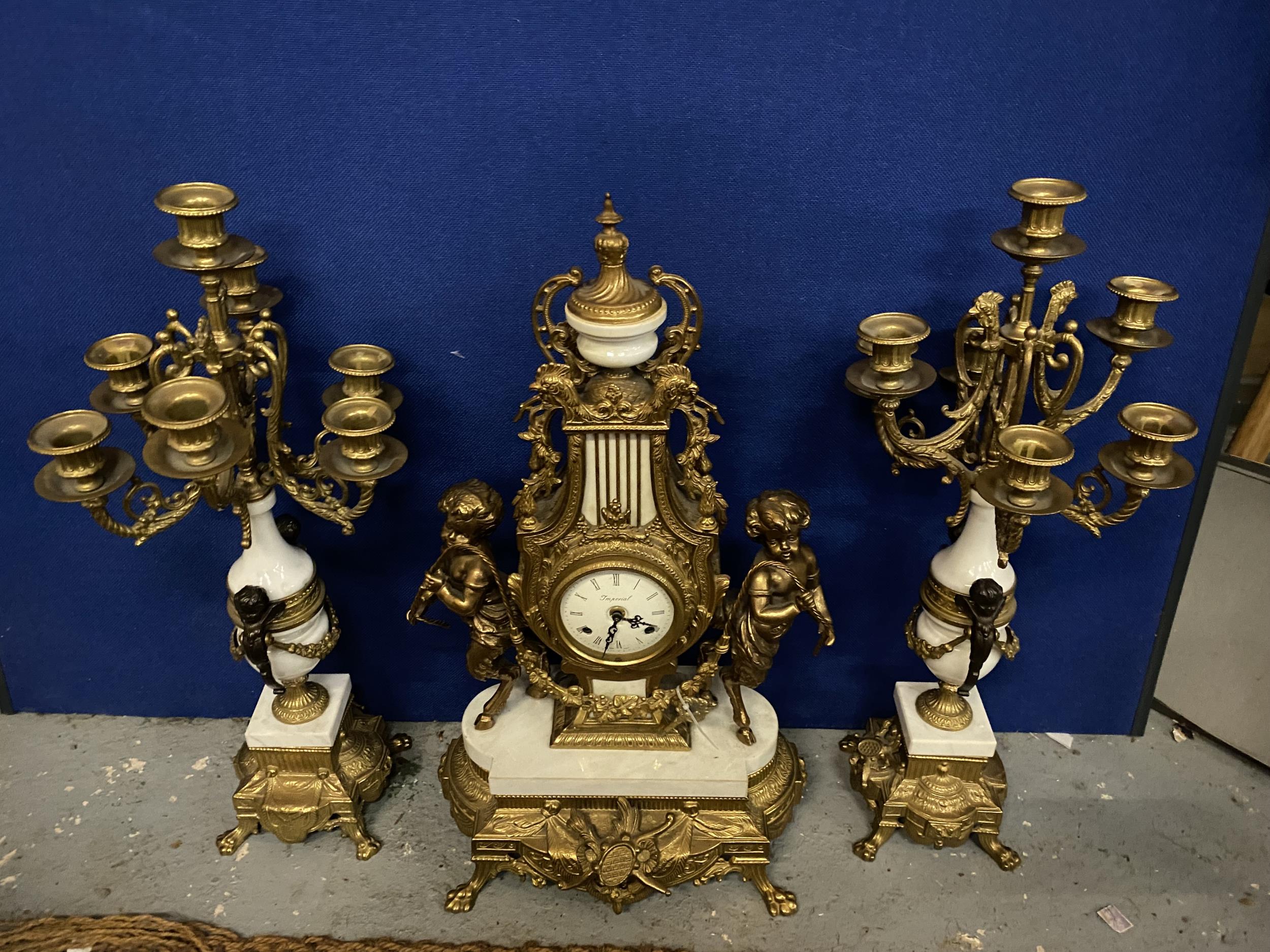 AN ORNATE IMPERIAL FRENCH GILT MANTLE CLOCK ON A MARBLE AND GILT BASE WITH CHERUB FAWN DECORATION