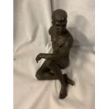 A RESIN FIGURINE OF A SEATED NAKED MAN