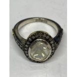 A CONTINENTAL WHITE AND YELLOW METAL RING WITH CENTRE DIAMOND AND SMALLER SURROUNDING DIAMONDS WHICH