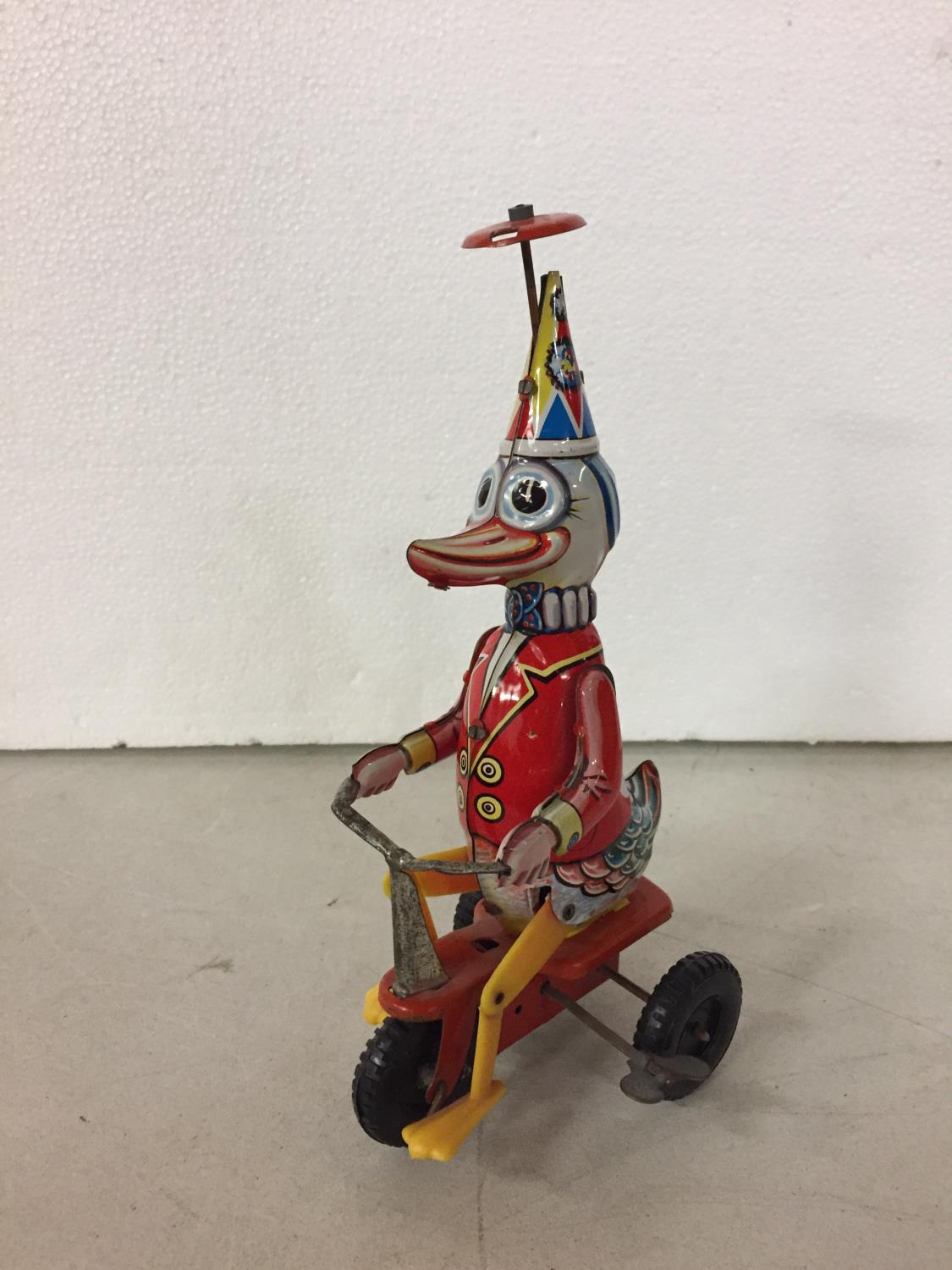 A TIN PLATE DUCK ON A BIKE TOY