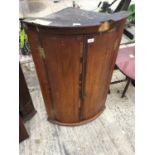 A GEORGIAN OAK BOW FRONTED CORNER CUPBOARD (SOME MOULDING MISSING)