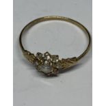 A 9 CARAT GOLD RING SUPPORTING A NINE CLEAR STONE FLOWER DESIGN WITH ARROW DESIGN SHOULDER SIZE O IN