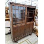 AN EARLY 20TH CENTURY OAK TWO DOOR GLAZED BOOKCASE WITH CUPBOARDS TO THE BASE, 57" WIDE. N.B. ONE