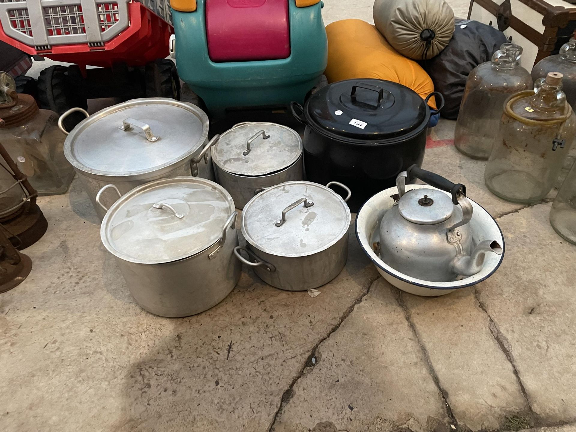 A GROUP OF FOUR LARGE STAINLESS STEEL COOKING POTS WITH LIDS, A LARGE BLACK ENAMEL COOKING POT