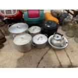 A GROUP OF FOUR LARGE STAINLESS STEEL COOKING POTS WITH LIDS, A LARGE BLACK ENAMEL COOKING POT