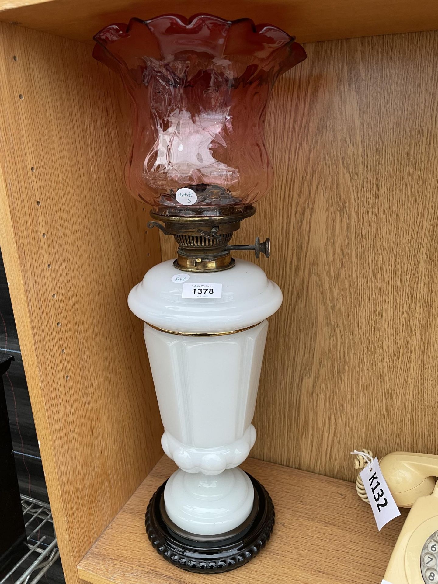 A LARGE GLASS OIL LAMP WITH RED GLASS SHADE
