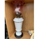 A LARGE GLASS OIL LAMP WITH RED GLASS SHADE