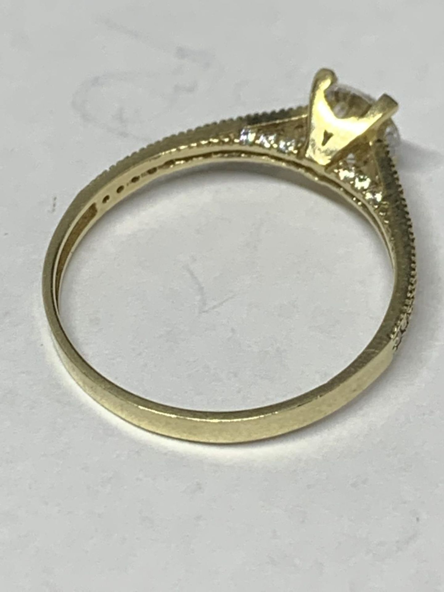 A 9 CARAT GOLD RING WITH A SINGLE CLEAR STONE AND CHIPS ON THE SHOULDERS SIZE O/P IN A - Image 3 of 4