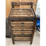 A VINTAGE WOODEN PRINTERS WORK STATION ENCLOSING TEN DRAWERS AND A SLOPPED WORK TOP WHICH ALSO