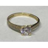 A 9 CARAT GOLD RING WITH A SINGLE CLEAR STONE AND CHIPS ON THE SHOULDERS SIZE O/P IN A