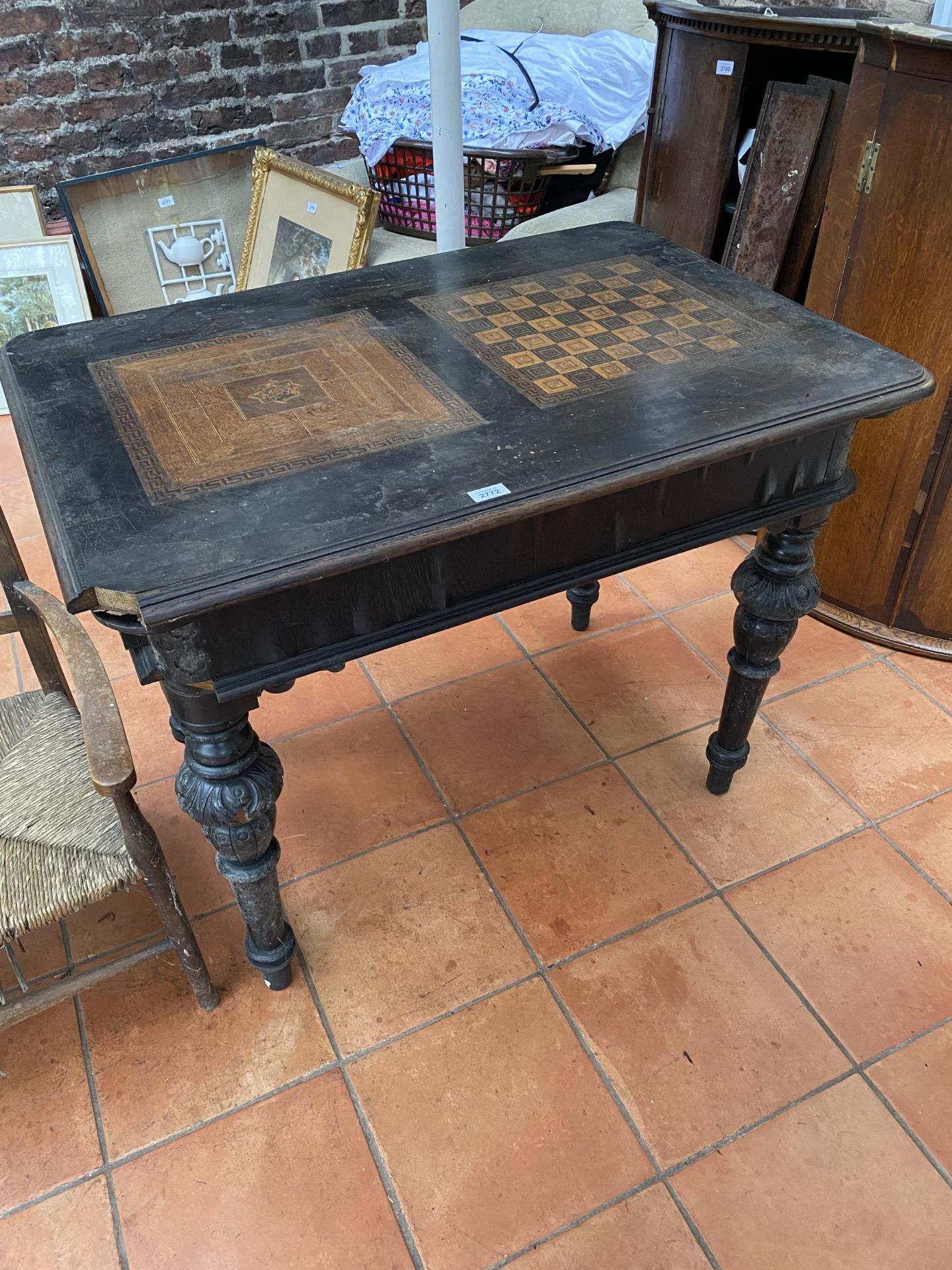 A VICTORIAN EBONISED GAMES TABLE WITH CHESS BOARD TOP AND TWO DRAWERS ON CARVED SUPPORTS 100CM X