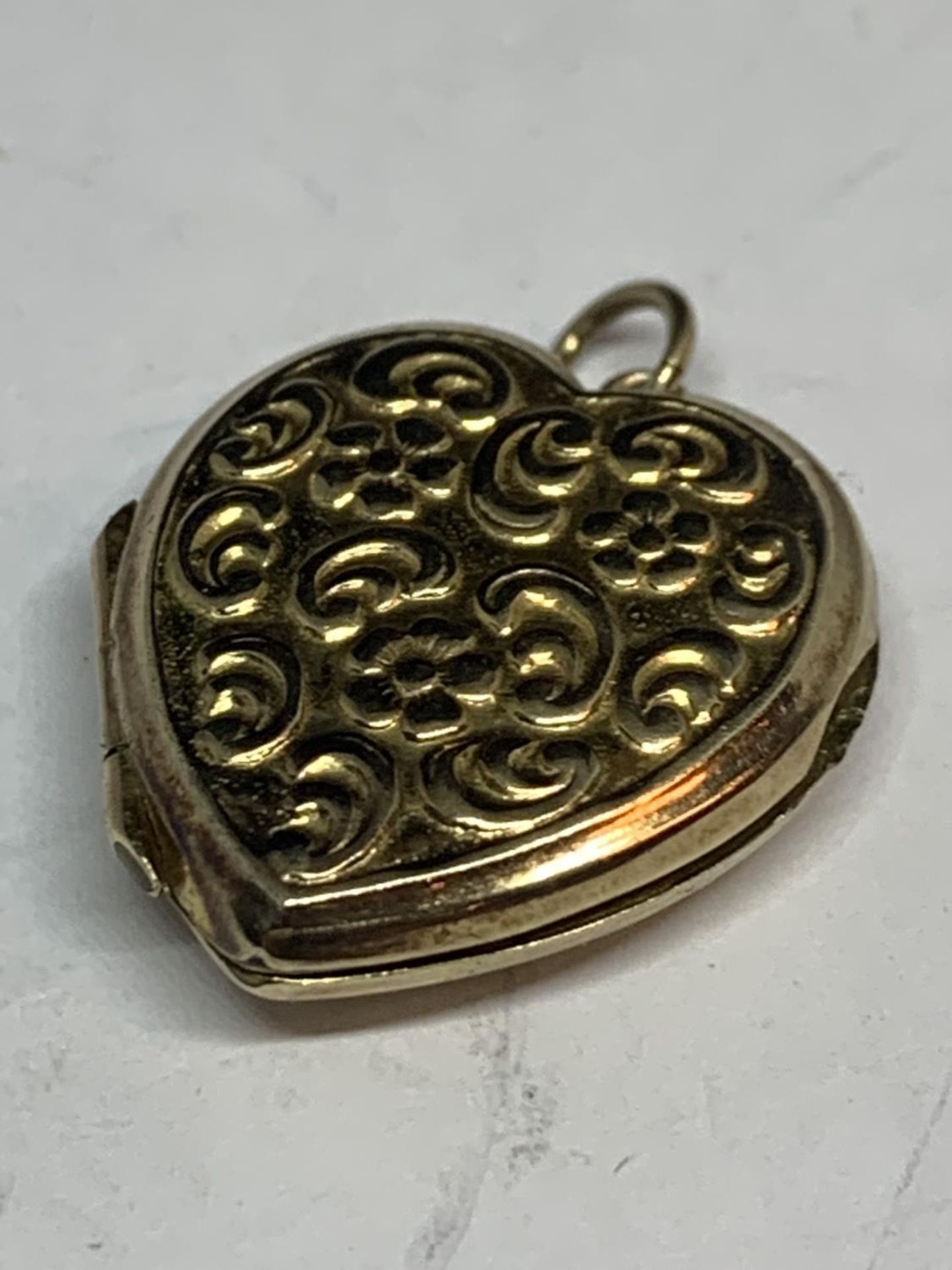 A 9 CARAT GOLD HEART SHAPED LOCKET WITH VINTAGE PHOTOGRAPHS GROSS WEIGHT 3.5 GRAMS