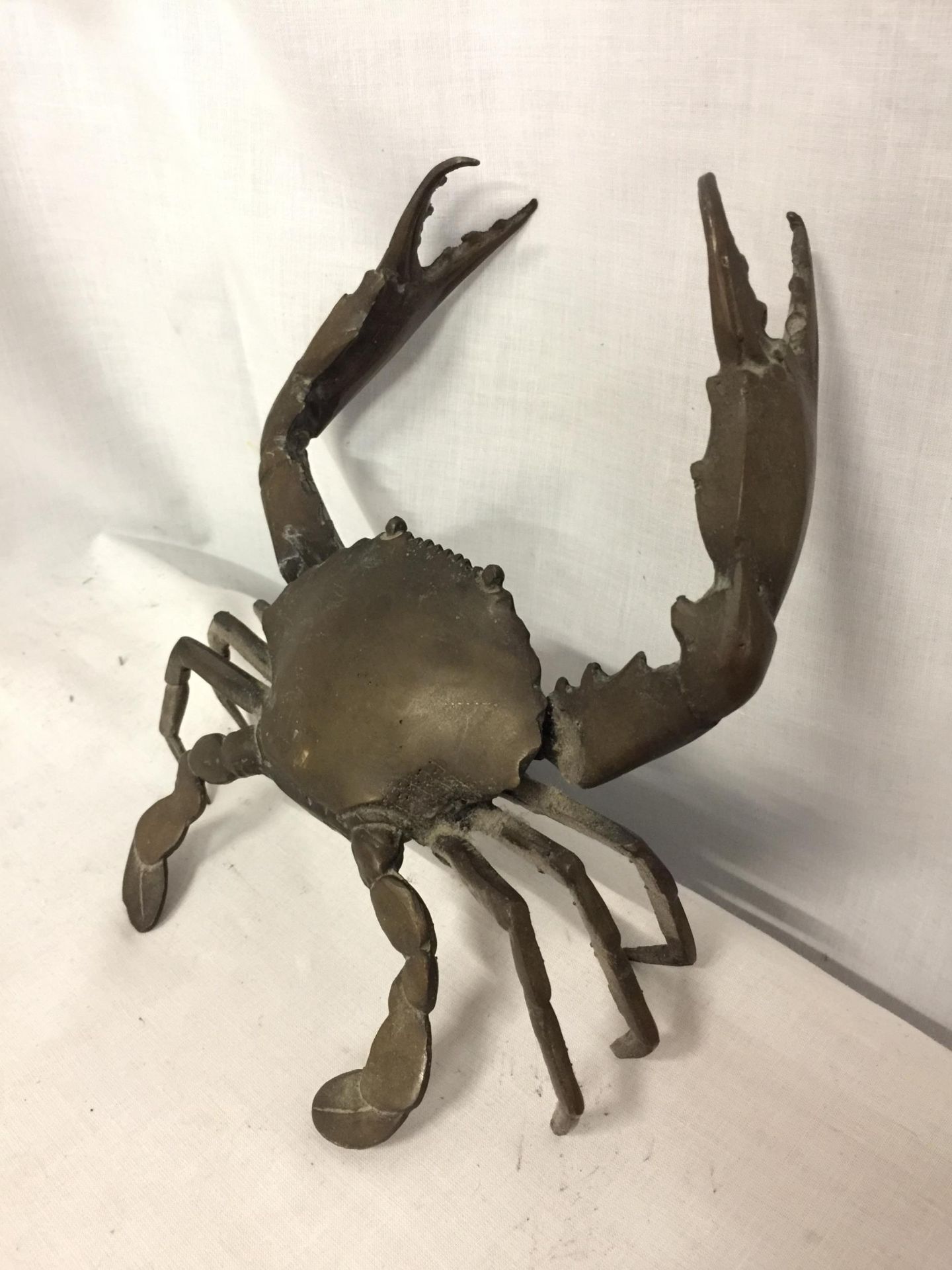 A POSSIBLY BRONZE RAISED CRAB ORNAMENT, ARM A/F