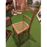 A PINE CHAIR WITH A CARVED BACK STRETCHER AND A RATTAN SEAT