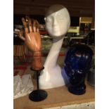A WOODEN ARTICULATED HAND, A BLUE GLASS HEAD AND A HEAD DISPLAY FOR HATS