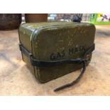 A GREEN PAINTED GAS MASK TIN