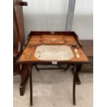 AN EDWARDIAN MAHOGANY FOLDING CAMPAIGN WRITING TABLE ON X-FRAME, WITH LEATHER FITTED INTERIOR, 24"