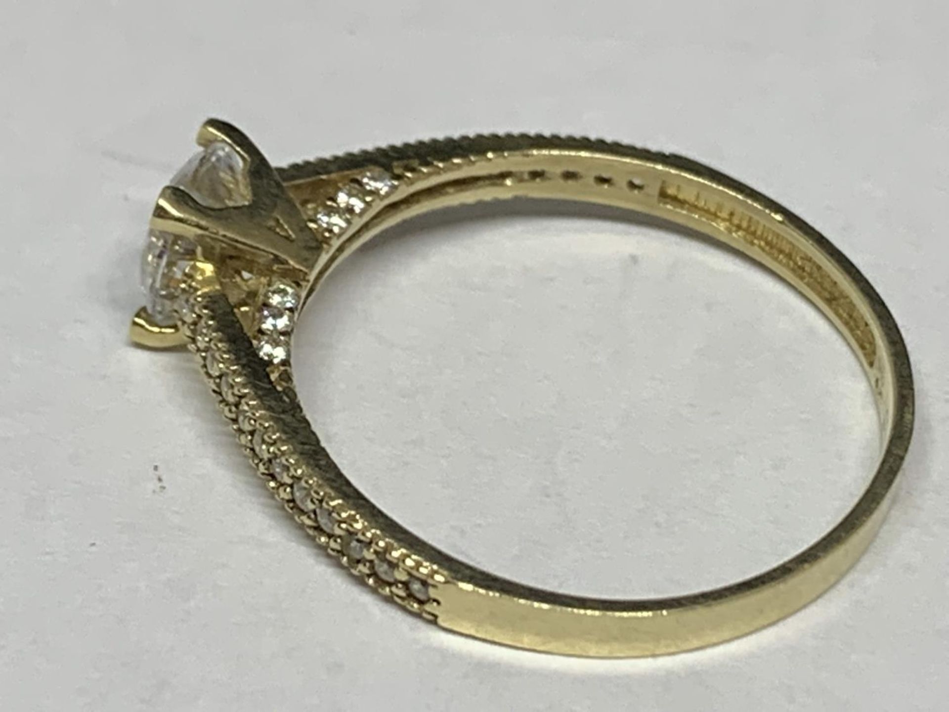 A 9 CARAT GOLD RING WITH A SINGLE CLEAR STONE AND CHIPS ON THE SHOULDERS SIZE O/P IN A - Image 2 of 4