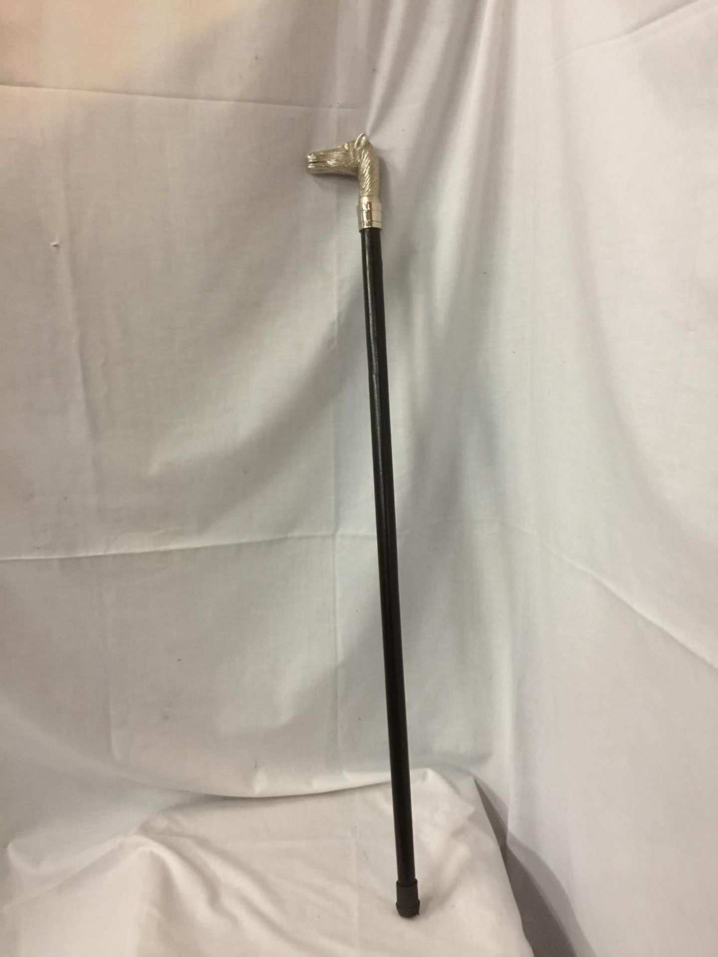 A WALKING CANE WITH A SILVER COLOURED HORSES HEAD TOP