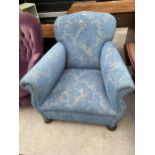 AN EDWARDIAN SPRUNG AND UPHOLSTERED EASY CHAIR ON FRONT BUN FEET