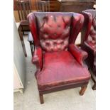 AN OXBLOOD BUTTON-BACK WINGED FIRESIDE CHAIR