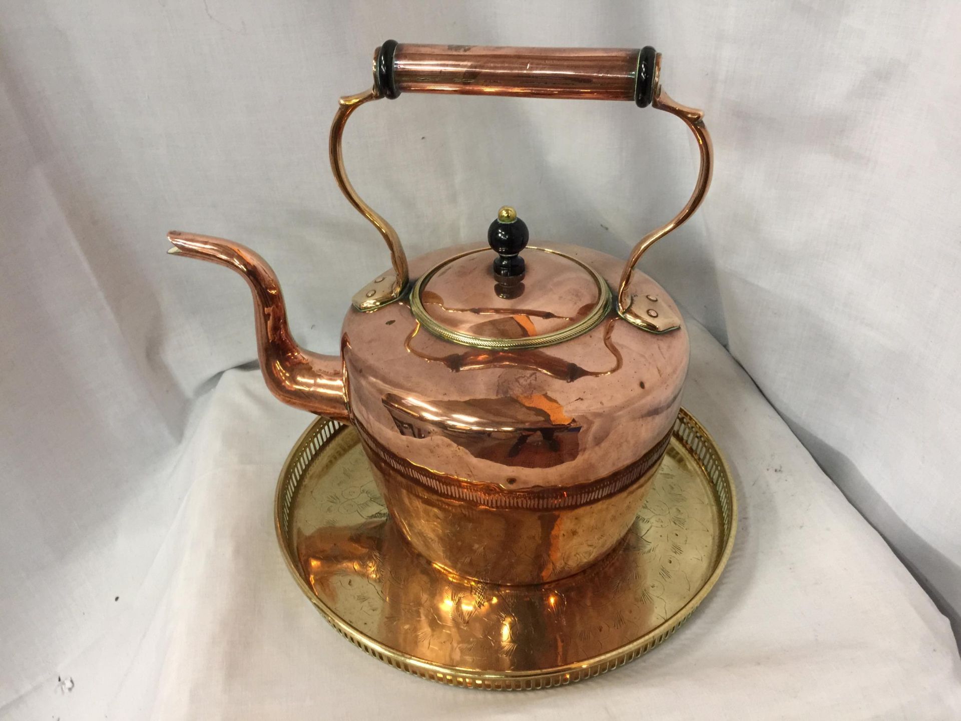 A LARGE COPPER KETTLE, HEIGHT 34CM, WIDTH 34CM TOGETHER WITH BRASS DECORATIVE TRAY DIAMETER 33CM