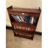 A MAHOGANY THREE TIER BOOKCASE CONTAINING VARIOUS BOOKS