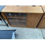 A RETRO TEAK BOOKCASE ENCLOSING TWO SLIDING GLASS DOORS AND CUPBOARD, 40" WIDE