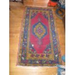 A RED AND BLUE PATTERNED RUG 183CM X 100CM