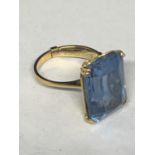 A TESTED TO 18 CARAT GOLD RING WITH A LARGE BLUE STONE BELIEVED AQUAMARINE AND A RING ADJUSTER