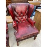 AN OXBLOOD BUTTON-BACK WINGED FIRESIDE CHAIR