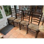 A SET OF FOUR LANCASHIRE STYLE OAK LADDER BACK DINING CHAIRS WITH RUSH SEATS