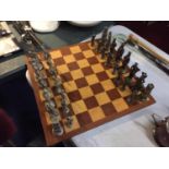 A COMPLETE CHESS SET WITH WOODEN BOARD AND METAL GREEK STYLE CHESS PIECES, BOARD 49CM X 49CM
