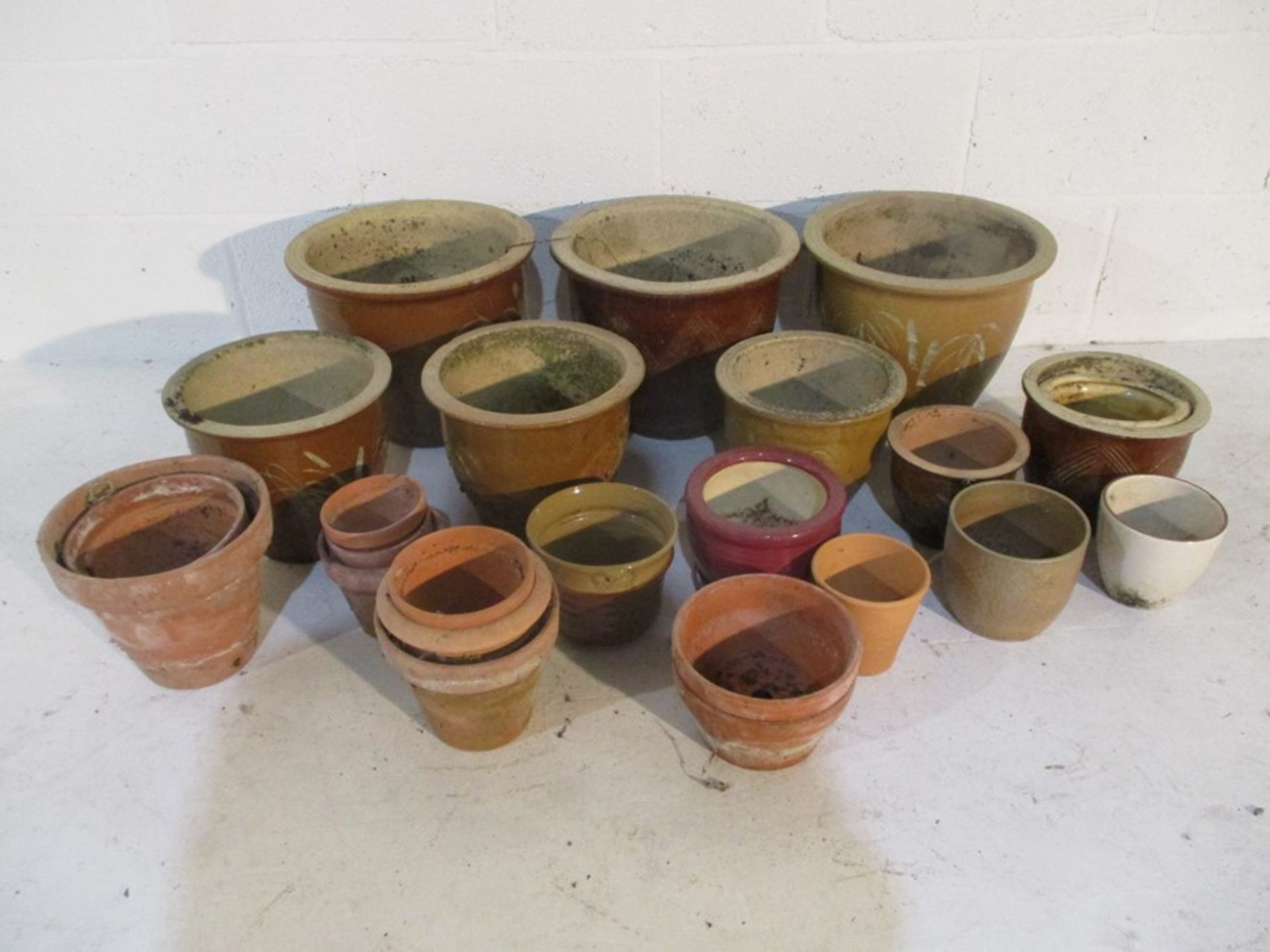 A collection of glazed and terracotta flower pots