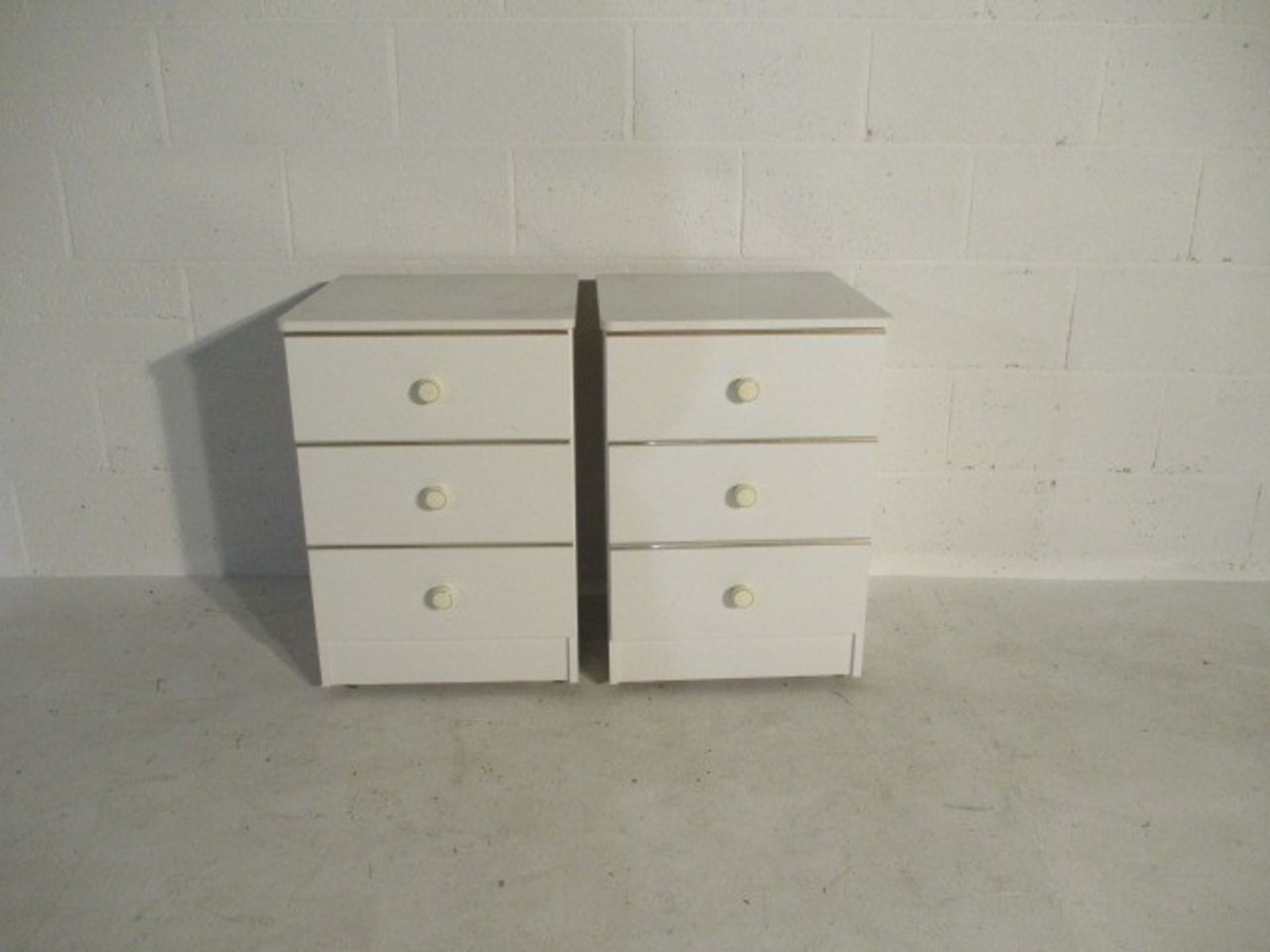 A pair of white bedside drawers along with one other