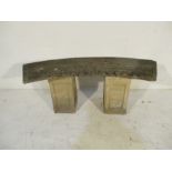 A concrete curved garden seat with miss-matched pillars