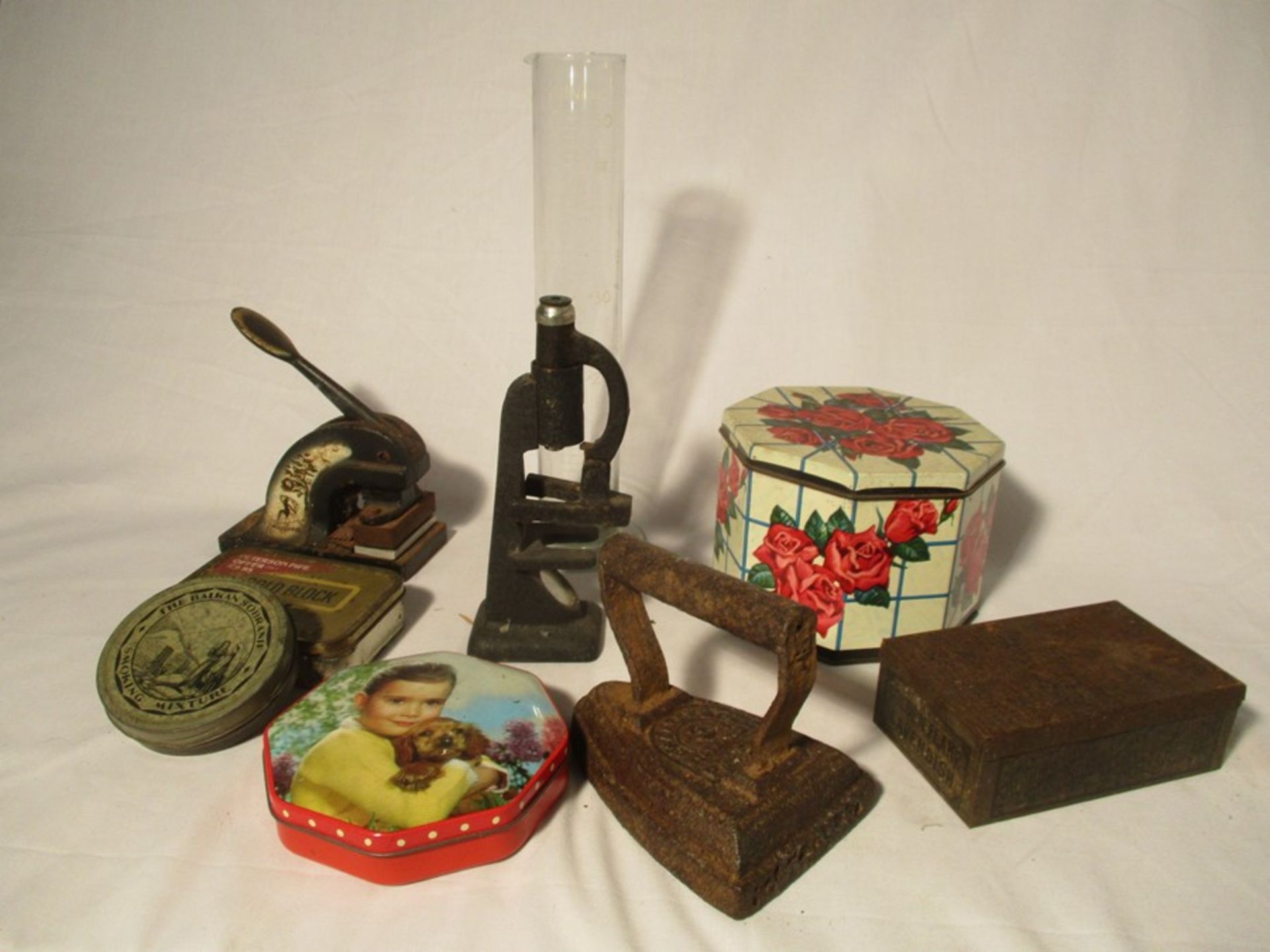 A collection of miscellaneous items including vintage tins, cast iron stamp, microscope ( A/F) etc.