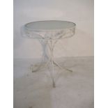 A wrought iron circular garden table with frosted glass top