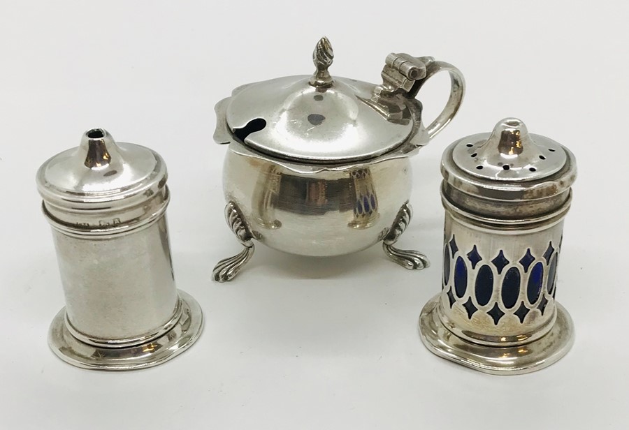 A hallmarked silver mustard pot with blue glass lining, along with silver salt and pepper pots