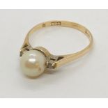 A 14ct gold ring set with a pearl flanked by two diamonds