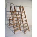 Two sets of wooden step-ladders, one with metal rails