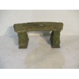 A curved concrete garden bench