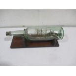 A four mast sailing boat in a bottle on wooden stand