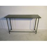 A metal framed workbench with painted green wooden top